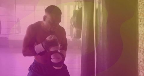 Boxer practicing in gym with punching bag