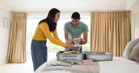 Young Couple Packing Suitcase for Vacation Adventure at Home