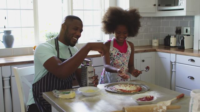 Father and daughter are preparing a homemade pizza in the kitchen, both smiling and enjoying the process. This video showcases family bonding during quarantine, perfect for depicting home activities, family fun, and culinary experiences. Ideal for use in articles about quarantine activities, recipes, family togetherness, and bonding moments.