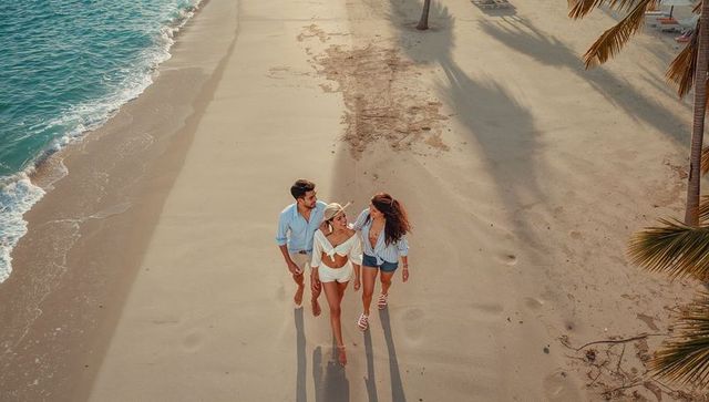 Walking friends along sunlit tropical beach leaving footprints near turquoise ocean