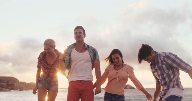 Group of young friends smiling and walking along a beach during sunset. Ideal for showcasing friendship, vacations, leisure activities, travel destinations, youth culture, and outdoor fun.