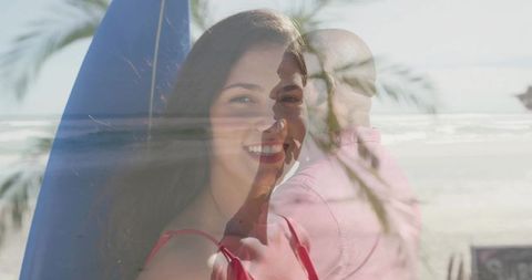 Smiling woman wearing red swimsuit with surfboard and superimposed man on sunlit beach