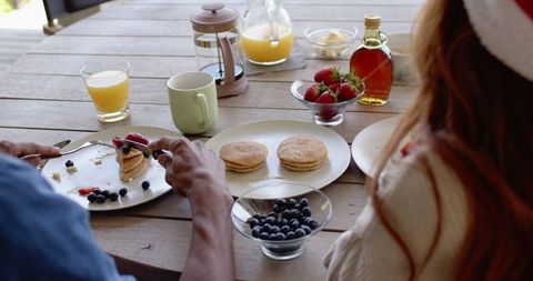 Couple Enjoying Breakfast Outdoors with Pancakes and Berries