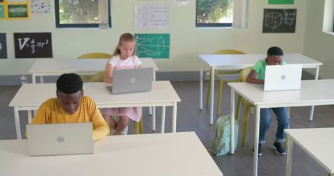 Multiethnic Elementary Students Using Laptops in Spacious Classroom Learning Math Technology