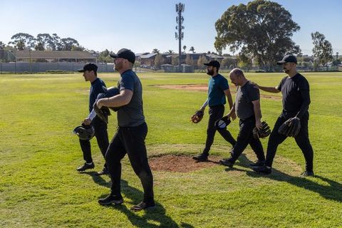 Postgame teammates walking across baseball field holding caps, gloves, helmets