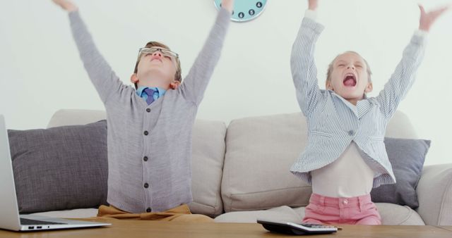 Happy children celebrating success with raised arms sitting on couch - Download Free Stock Images Pikwizard.com