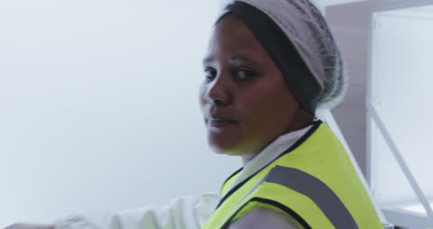 Female Worker in High Visibility Vest Checking Factory Production