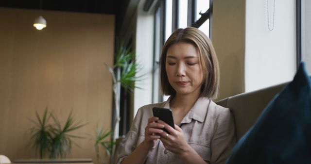 Woman Using Smartphone in Modern Office with Natural Lighting - Download Free Stock Images Pikwizard.com