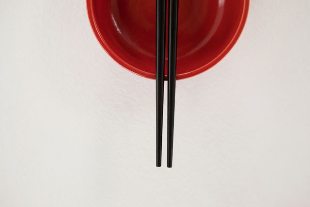 Pair of chopsticks over a bowl against white background