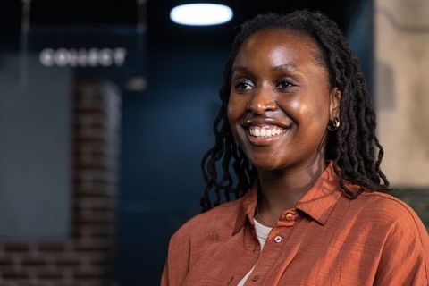 Smiling african woman wearing rust shirt and gold hoop earrings in cozy cafe interior
