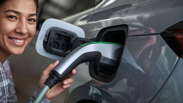 Smiling driver inserting EV connector into sleek electric car in garage charging moment