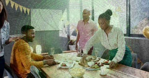Friends serving homemade bread and wine at cozy sunlit dining table for gathering
