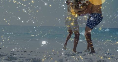Jumping couple embracing on sunlit beach with sparkling bokeh overlay, summer romance