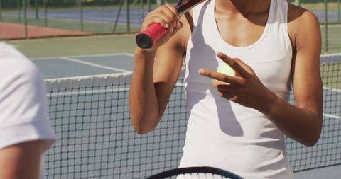 Female Tennis Player Signaling Near Net Holding Racket and Ball on Outdoor Court
