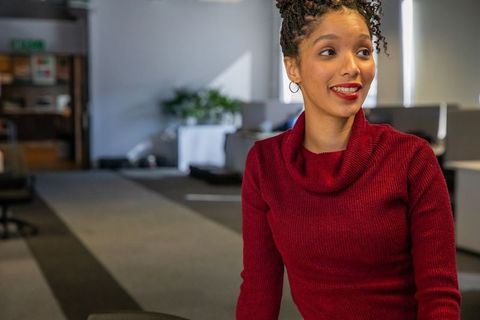 Confident african american woman smiling leaning in modern open-plan office workspace