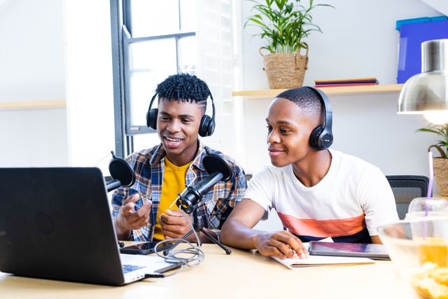 African american teenage male friends with laptop and microphones recording podcast. Hanging out with friends and spending quality time together concept.