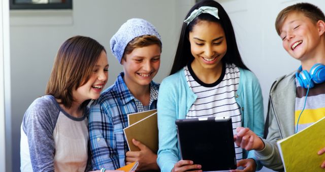 Teenage students gathered together engaging with a tablet, showing collaborative learning. Perfect for educational websites, school promotional materials, and articles about technology in education.