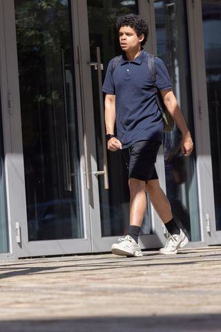 African american man walking past glass doors carrying backpack urban commuter lifestyle