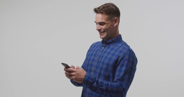 Young man smiling while using smartphone - Download Free Stock Images Pikwizard.com