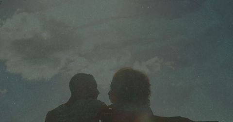 Couple Sharing Intimate Moment at Dusk Against Cloudy Sky