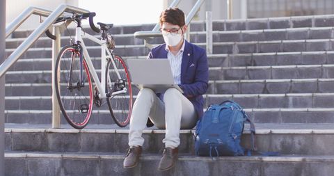 Asian Businessman Using Laptop Wearing Face Mask on Outdoor Stairs