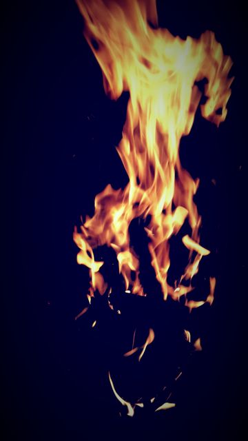 This image captures a close-up of bright, intense flames against a dark background, creating a striking contrast and an atmosphere of heat and energy. Perfect for use in presentations or projects related to fire safety, energy, or warmth. Ideal for websites or articles discussing the elements, fire pits, or campfires. Can be used for dramatic backgrounds in graphic design and advertisements.