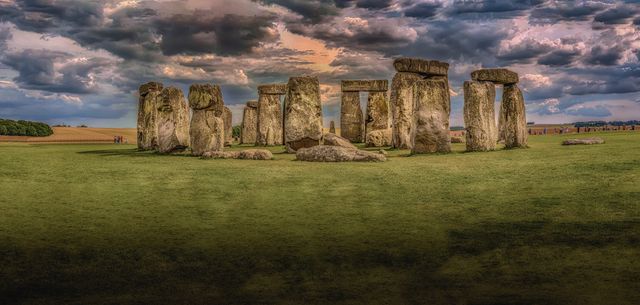 Panoramic view of Stonehenge at sunset with dramatic clouds in the sky. Ideal for content related to travel, history, archeology, British landmarks, tourism promotions, cultural heritage, and ancient mysteries.