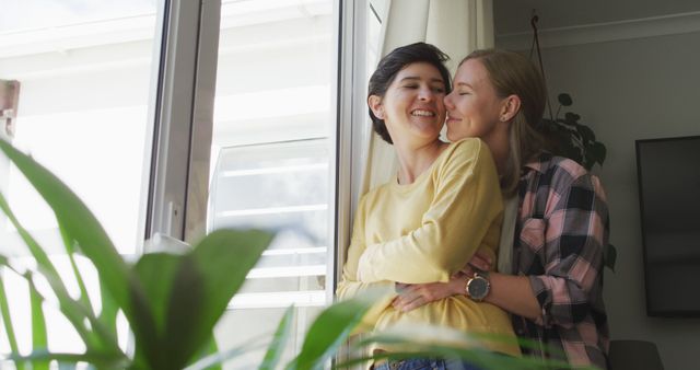 Caucasian lesbian couple embracing each other near the window at home. lgbt relationship and lifestyle concept