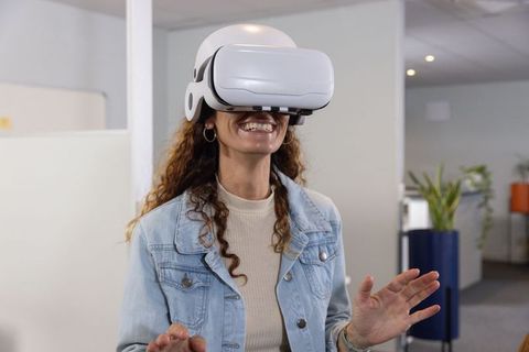 Mature Woman Wearing White VR Headset Exploring Virtual Reality in Modern Office