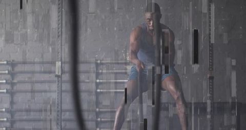 Muscular athlete performing battle ropes exercise in gym setting