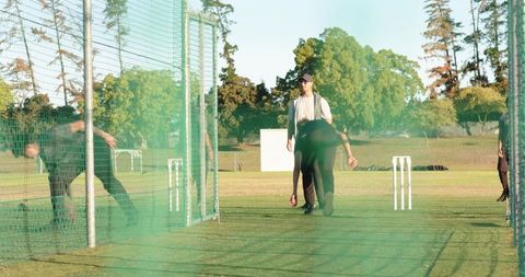 Fast bowler delivering ball in net practice session on sunny cricket training ground