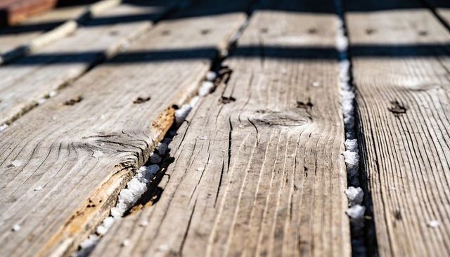 Weathered wooden deck planks with frost in gaps close-up rustic texture background