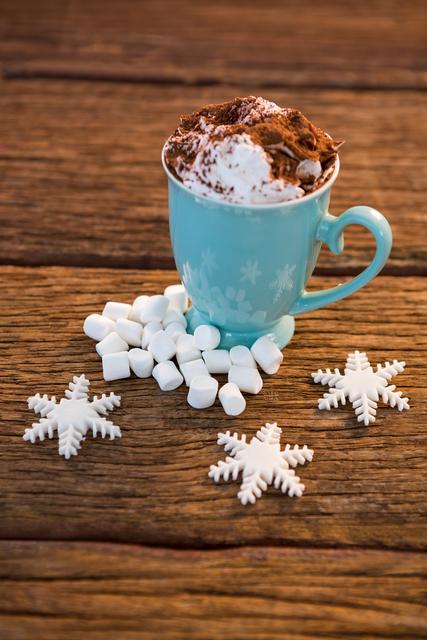 Cup of coffee with snowflake and marshmallow on wooden plank during christmas time