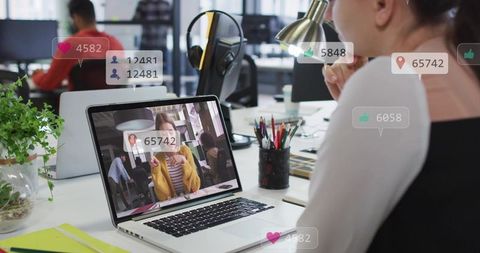 Watching livestream on laptop with social media engagement overlays in coworking office