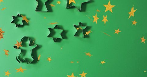 Christmas cookie cutters on green background with gold stars