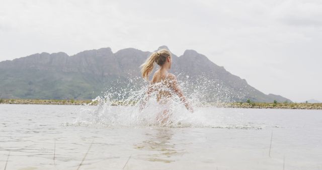 Woman Splashing in Water with Mountain in Background - Download Free Stock Photos Pikwizard.com