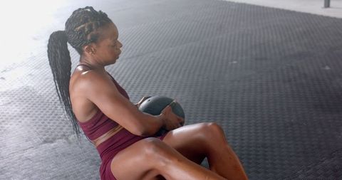 Fit Woman Exercising Core with Medicine Ball in Gym