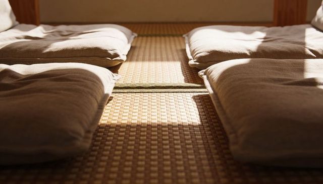 Sunlight streaming on tatami, four zabuton cushions creating calm minimalist japanese room