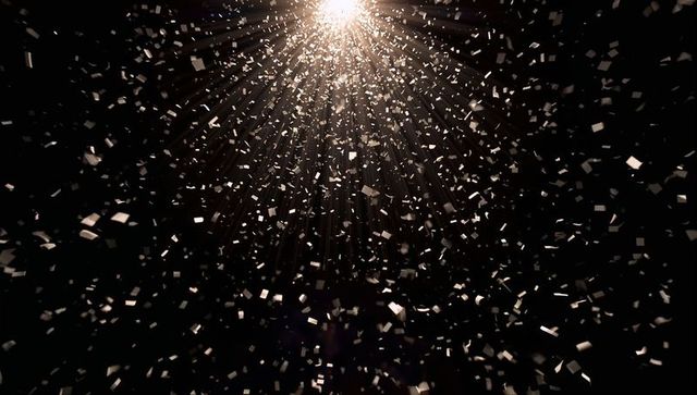 Shimmering Metallic Confetti Falling Through Spotlight Beams on Dark Background
