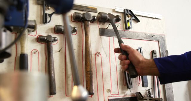 Welder taking hammer from tool rack in workshop 4k