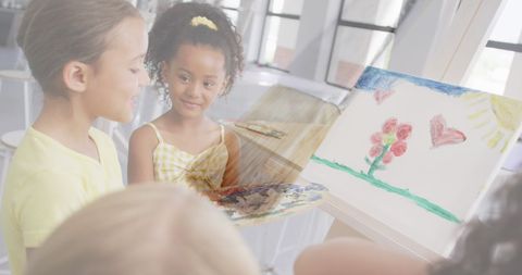 Young diverse schoolgirls are engaging in a creative art class, using vibrant colors to paint. Their cheerful expressions highlight themes of friendship and active learning, making this an ideal image for educational content promoting creativity, school programs, and child development activities.