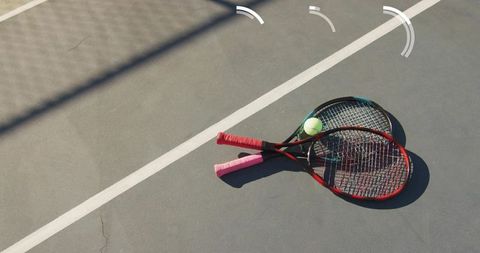 Crossed Tennis Rackets Resting on Outdoor Hard Court with Tennis Ball and Line