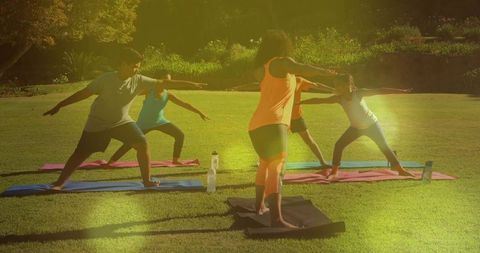 Kids yoga class in park with instructor leading warrior ii poses and water bottles