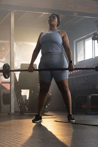 African american woman lifting barbell deadlift in industrial gym showing strength focus