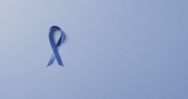 Image of dark blue colon cancer ribbon on pale blue background. medical and healthcare awareness support campaign symbol for colon cancer.