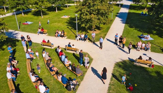 Community gathering in park with benches, families and children enjoying summer sunshine