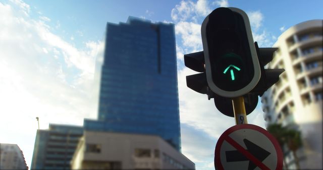 Photo captures an urban cityscape with modern buildings and a green traffic light indicating forward movement. Ideal for illustrating urban living, professional articles on traffic management, or city infrastructure highlights. Can be used in projects related to transportation, architecture, or urban development.