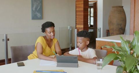 Mother Helping Son with Tablet Homework at Home Table Learning Together