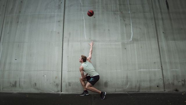 Athlete reaching for basketball against concrete wall backboard urban outdoor training