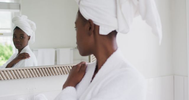 Woman in bathrobe with towel on her head looking in mirror - Download Free Stock Images Pikwizard.com